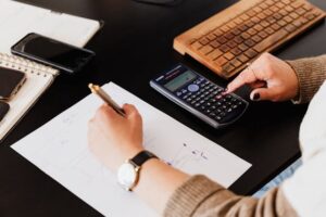 會計師拿著筆，用桌上的計算機正在工作